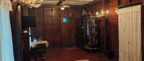 A room with wooden walls, a chandelier, a cabinet, and a bed.