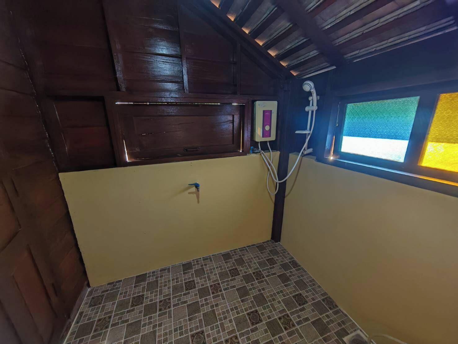 A small, enclosed bathroom with a shower, a toilet, and a window.