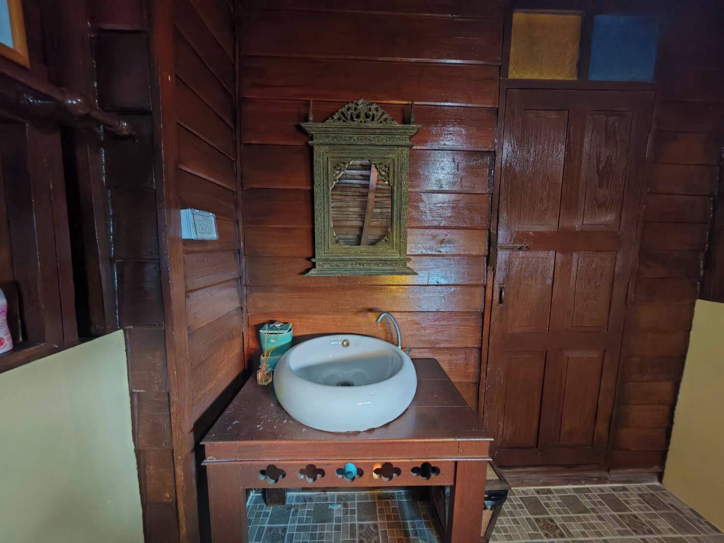 Une salle de bain en bois avec un lavabo blanc, un miroir au-dessus et un meuble en dessous.
