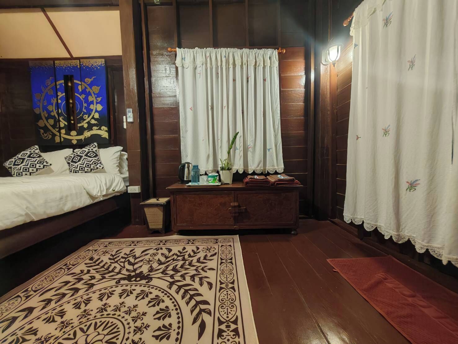A bedroom with a bed, a nightstand, a dresser, and a window with curtains.