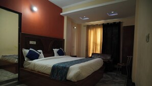 A hotel room with a large bed, a desk, and a chair. - Shree Hari palace (Vrindavan)