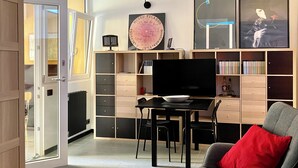 A modern living room with a dining area, featuring a flat-screen TV, a dining table with chairs, a bookshelf, and a large framed artwork on the wall. - BEAUTIFUL LOFT bright and comfortable, near the Roman Forum and Colosseum (Roma)