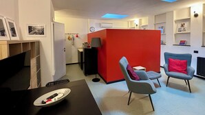 A modern living room with a red partition, two grey armchairs with red cushions, a black table with a remote control, and a skylight above. - BEAUTIFUL LOFT bright and comfortable, near the Roman Forum and Colosseum (Roma)
