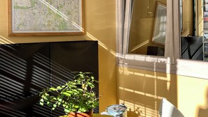 A small, sunlit room with a yellow wall, a map, a potted plant, a glass ashtray, and a white chair. - BEAUTIFUL LOFT bright and comfortable, near the Roman Forum and Colosseum (Roma)