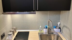 A modern kitchen with a stainless steel sink, a black induction cooktop, and wooden cabinets. - BEAUTIFUL LOFT bright and comfortable, near the Roman Forum and Colosseum (Roma)