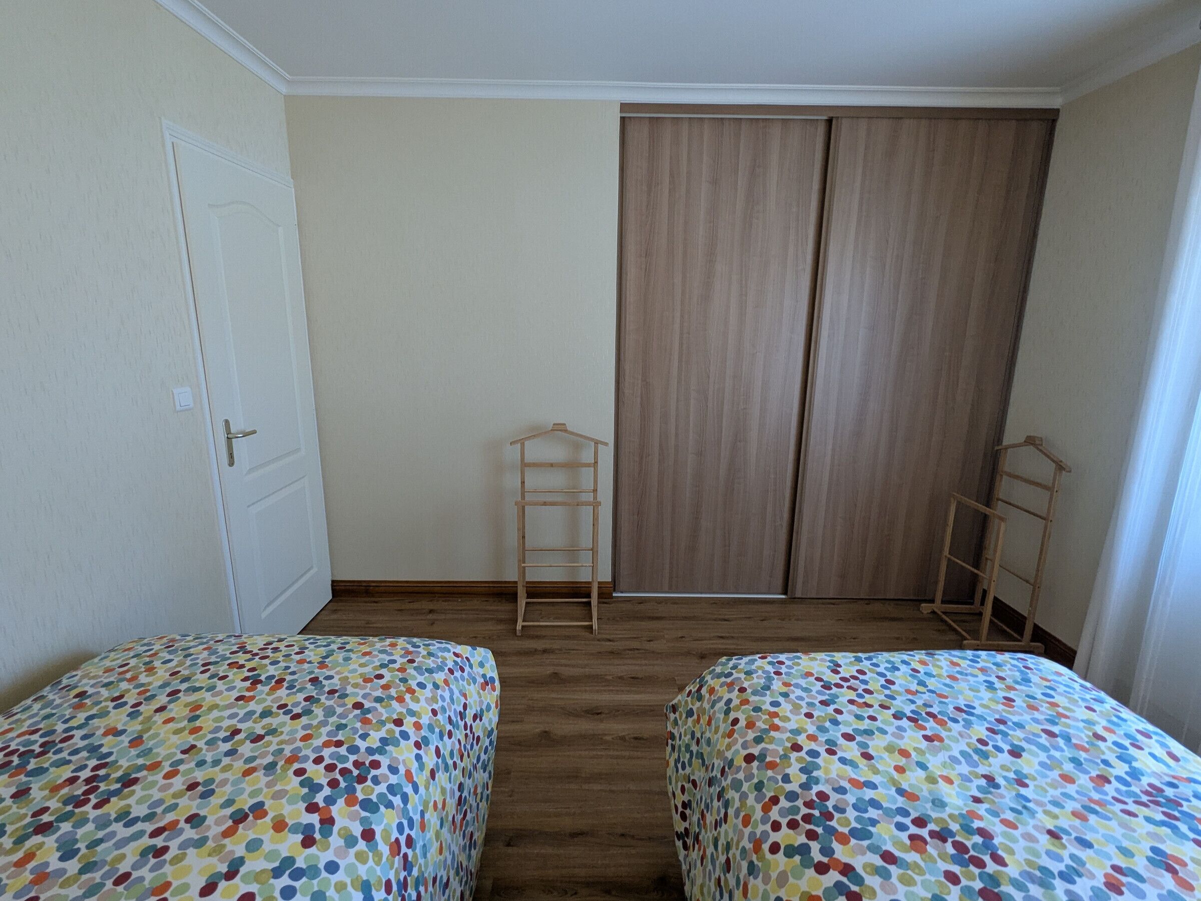 Une chambre avec deux lits, une armoire et une porte.
