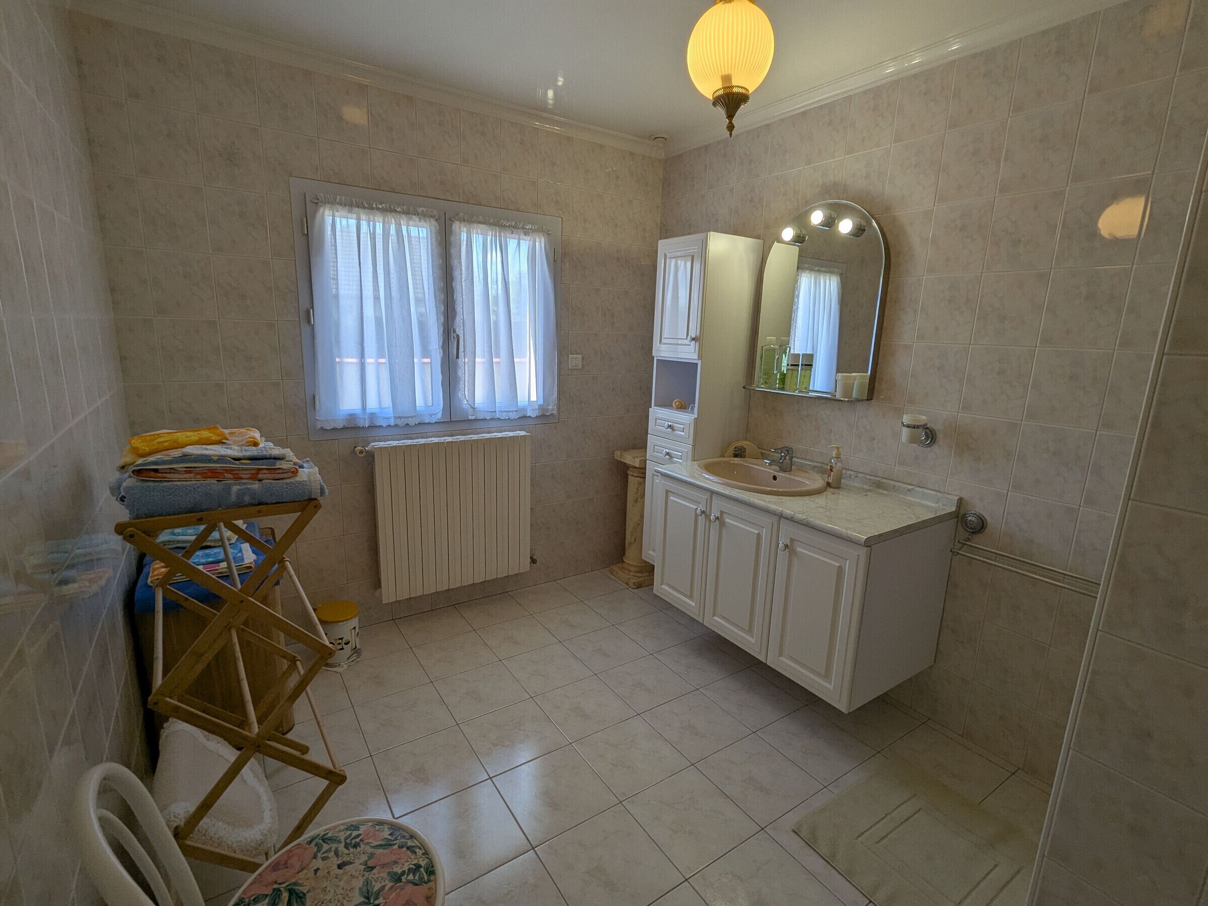 A bathroom with a sink, mirror, and window with curtains.
