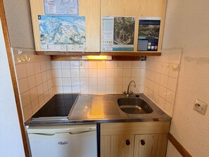 A compact kitchen with a sink, stove, and a dishwasher. Above the counter, there are informational posters. - Studio 3 pers, slopeside with balcony (Les Adrets-Prapoutel)