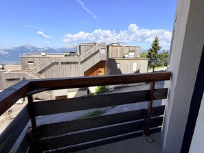 A balcony with a wooden railing overlooking a mountainous landscape.