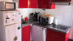 A compact kitchen with red cabinets, a microwave, a toaster, and a dishwasher. - Quiet Air-Conditioned Apartment with Parking Near Center and Beach for 4 (Cap d'Agde)