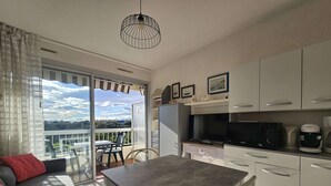 Uma cozinha moderna com armários brancos, uma mesa de jantar e uma varanda com vista.