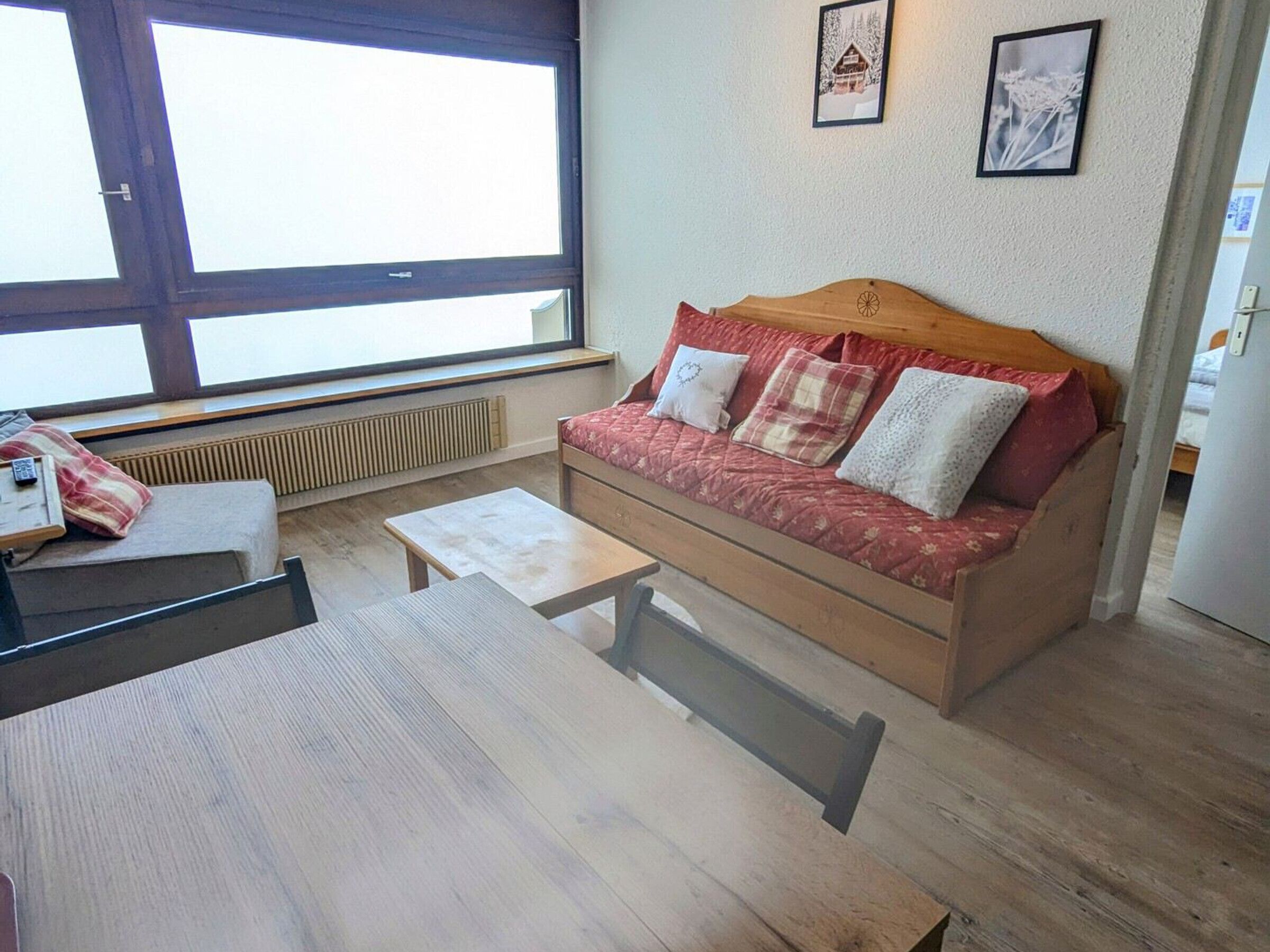 Een gezellige kamer met een houten bank, een klein tafeltje en een raam met jaloezieën.
