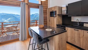 A modern kitchen with wooden cabinets, a black countertop, and a built-in microwave. - Spacious duplex in Les Saisies for 8 people with parking included (Les Saisies)