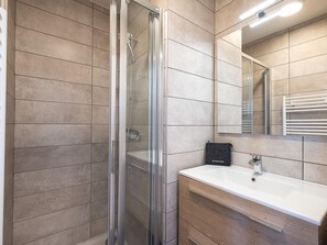 Une salle de bain moderne avec une douche à parois de verre, un lavabo blanc et un miroir au-dessus.