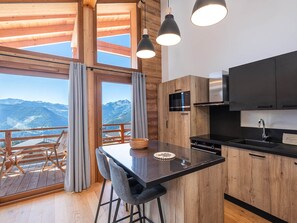 Eine moderne Küche mit Holzausstattung, einer schwarzen Arbeitsplatte und einer eingebauten Mikrowelle.
