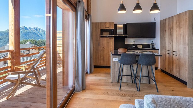 A modern kitchen with wooden cabinets, a central island, and pendant lighting. - Spacious duplex in Les Saisies for 8 people with parking included (Les Saisies)