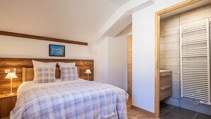 A bedroom with a wooden headboard, a bed with a plaid blanket, two bedside lamps, and a wooden wardrobe with a towel rack. - Spacious duplex in Les Saisies for 8 people with parking included (Les Saisies)