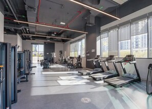 A gym with treadmills, weight machines, and exercise mats. - Bloomfields Stylish 1BR The Bridges  (Abu Dhabi)