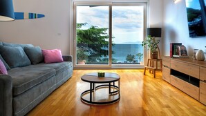 A modern living room with a sofa, a round coffee table, and a TV mounted on the wall.