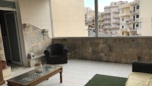 Un balcone con una divisa, una sedia, un tavolino e vista su una zona residenziale.