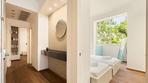 Un dormitorio moderno con un ventanal grande, una mesita de noche y un banco empotrado.