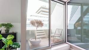 A modern balcony with a potted plant, a chair, and a view of a building. - JULIUS 23: Cozy Stay - 5 Mins to City Center (Wien)