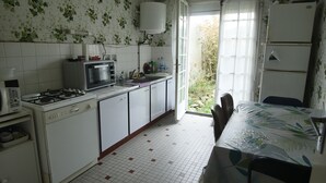 Una cocina compacta con armarios blancos, estufa a gas, microondas y refrigerador.