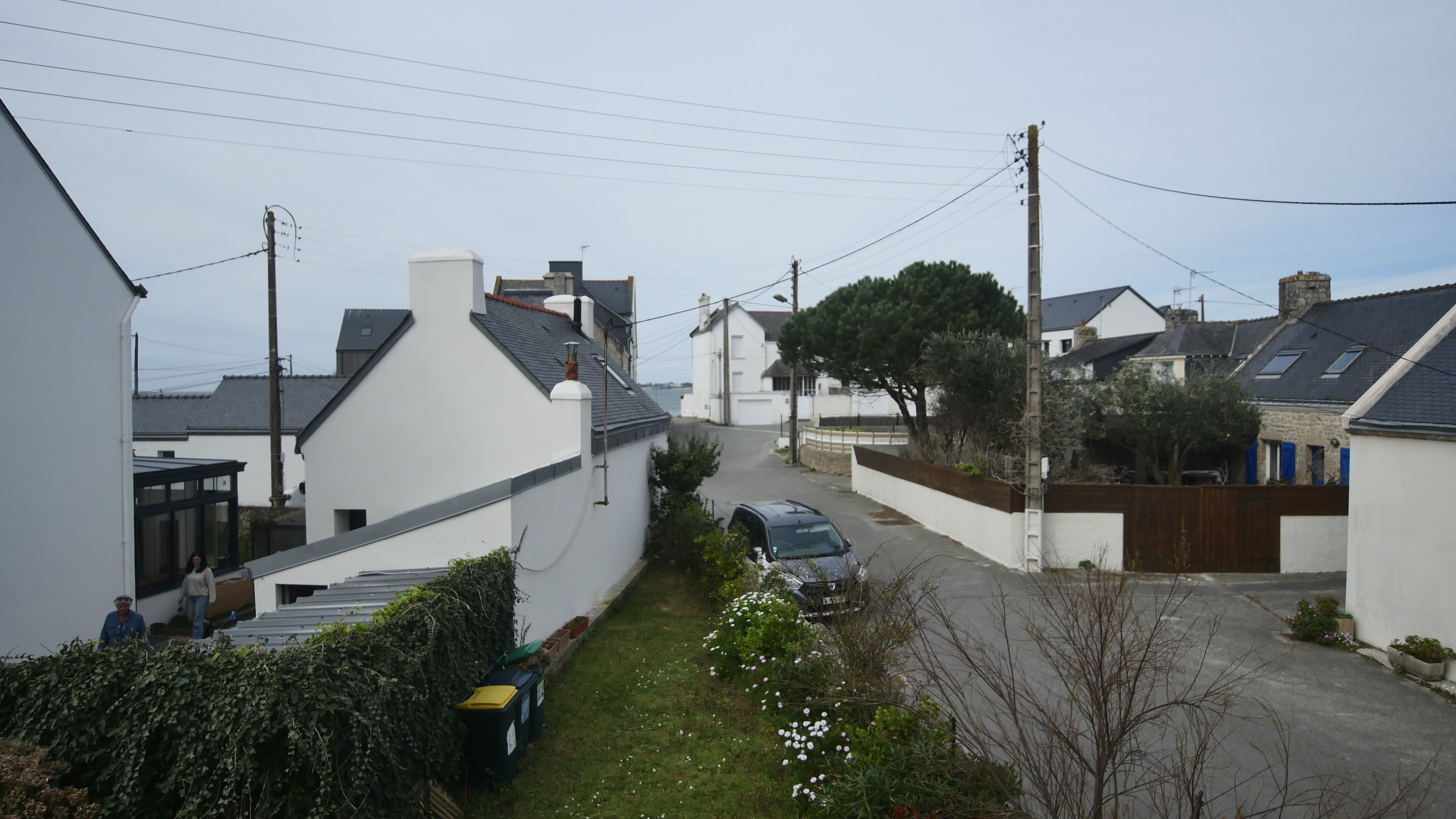 Una calle residencial con casas, un automóvil estacionado y cielo despejado.