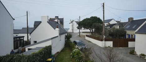 Una calle residencial con casas, un automóvil estacionado y cielo despejado.