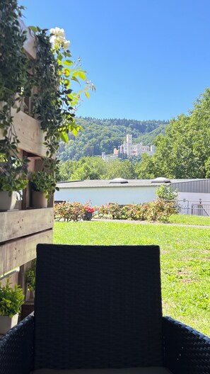 A wicker chair facing a view of a castle, a lake, and a forested hill. - Apartment Lahneck - 10 min to Koblenz. For an active or relaxing vacation on the Middle Rhine (Lahnstein)
