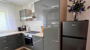 Een moderne keuken met grijze kastjes, een zwarte koelkast en een houten vloer.