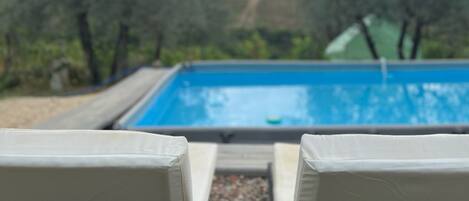 Una piscina al aire libre de temporada, sombrillas