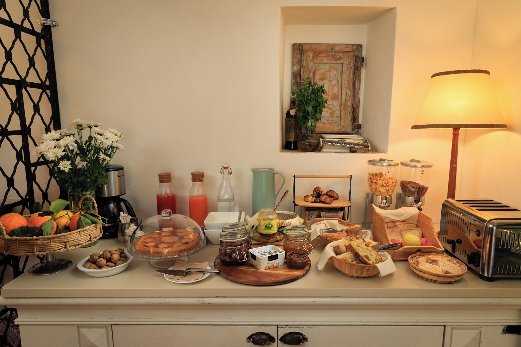 Um buffet de café da manhã com diversos alimentos, uma máquina de café e um abajur.