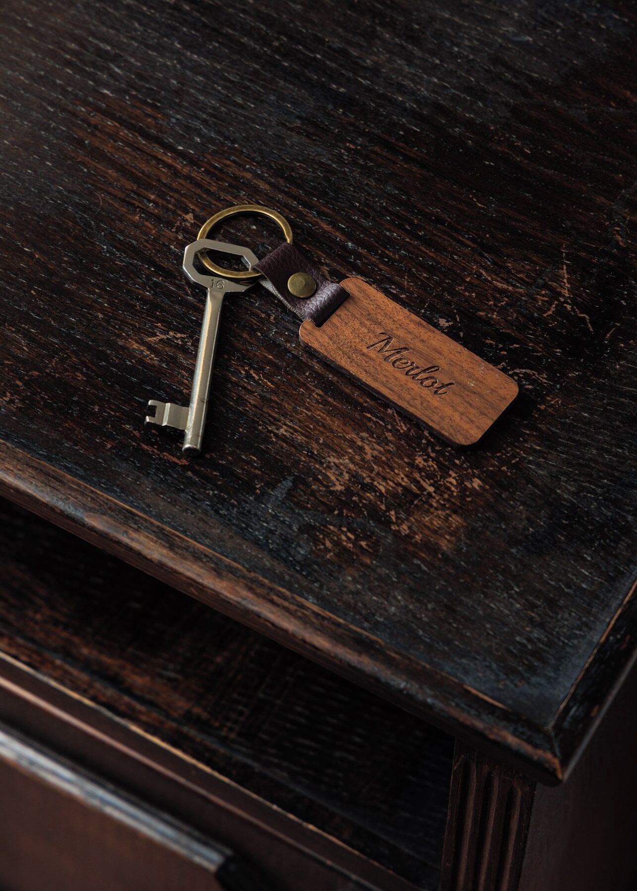 Een sleutel met een houten label op een donker houten oppervlak.