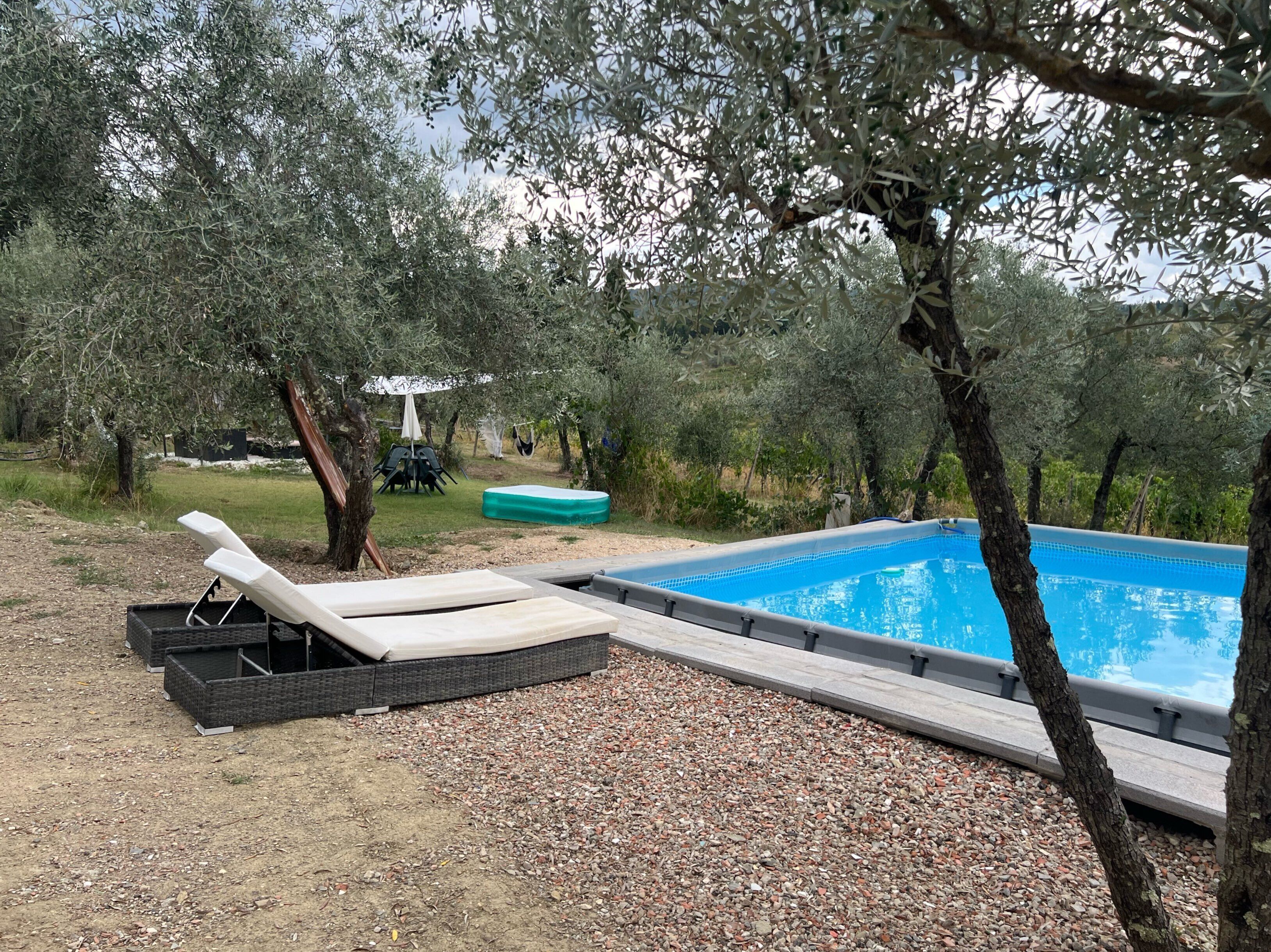 A poolside area with a pool, lounge chairs, and a small table.