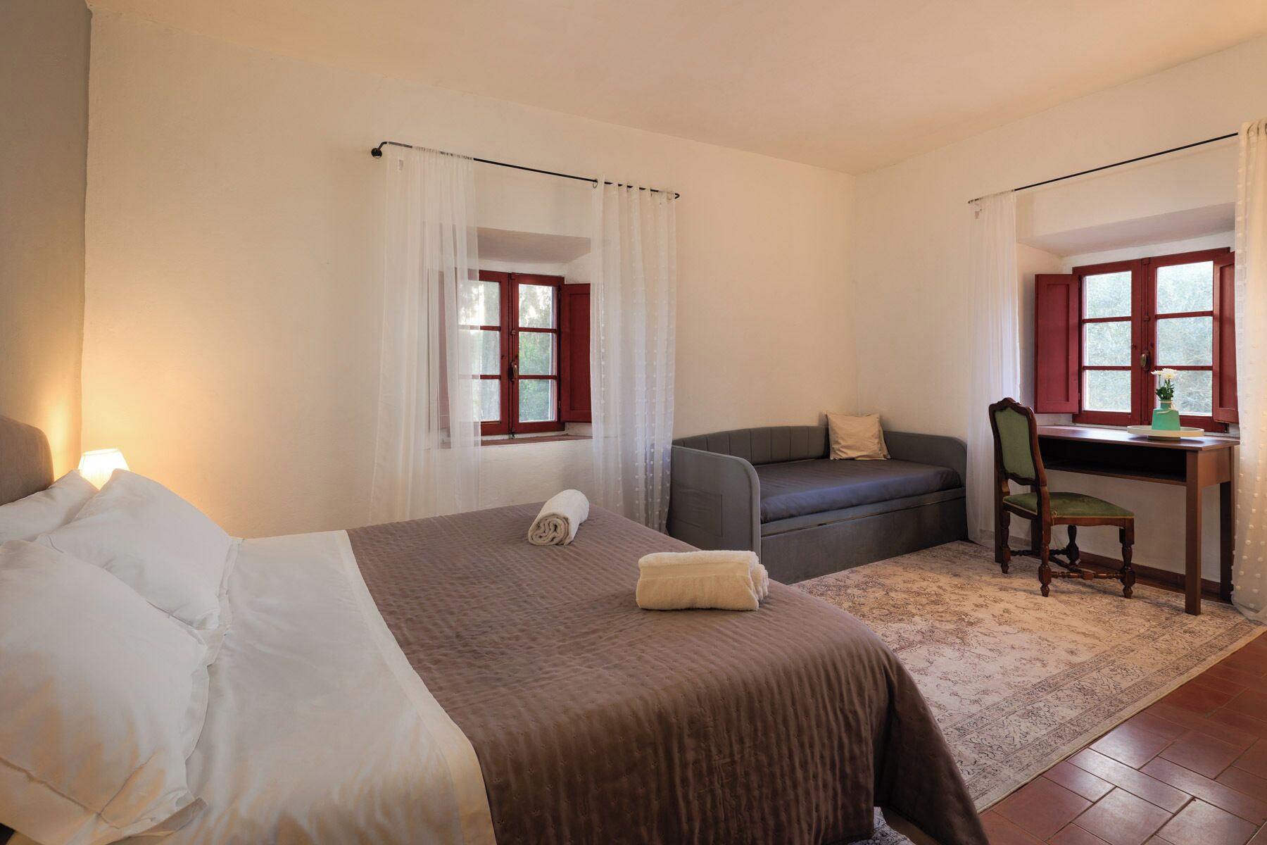 Un dormitorio con cama, escritorio, silla y sofá.