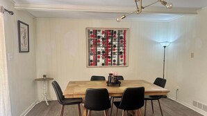 A dining area with a wooden table, black chairs, and a decorative wall piece.
