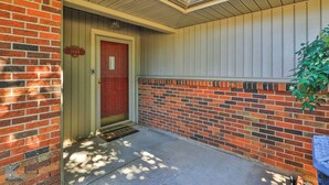 A building entrance with a red door, a mailbox, and a brick wall.