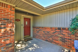 A building entrance with a red door, a mailbox, and a brick wall.