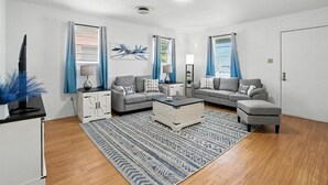 Een moderne woonkamer met twee grijze banken, een witte salontafel en een kamerkleed met een patroon.