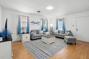 Ein modernes Wohnzimmer mit zwei grauen Sofas, einem weißen Couchtisch und einem gemusterten Teppich.