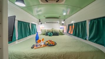Ein Zimmer mit einem Bett, Vorhängen, einem Tisch mit Speisen und einer Deckenleuchte.