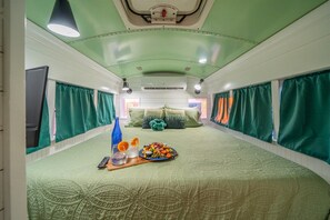 A room with a bed, curtains, a table with food, and a ceiling light. - Oasis Pool- Schoolie | Heated Pool and Hot Tub! (Abilene)