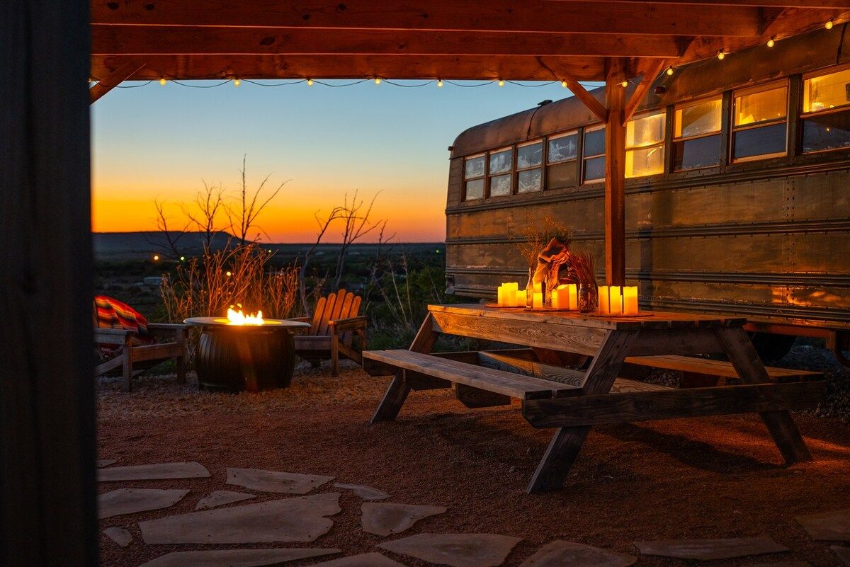 An outdoor seating area with a fire pit, candles, and a wooden bench.