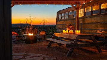 An outdoor seating area with a fire pit, candles, and a wooden bench.