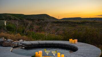 Ein Whirlpool mit Kerzen und einer Schüssel Essen, eingebettet in eine natürliche Landschaft.