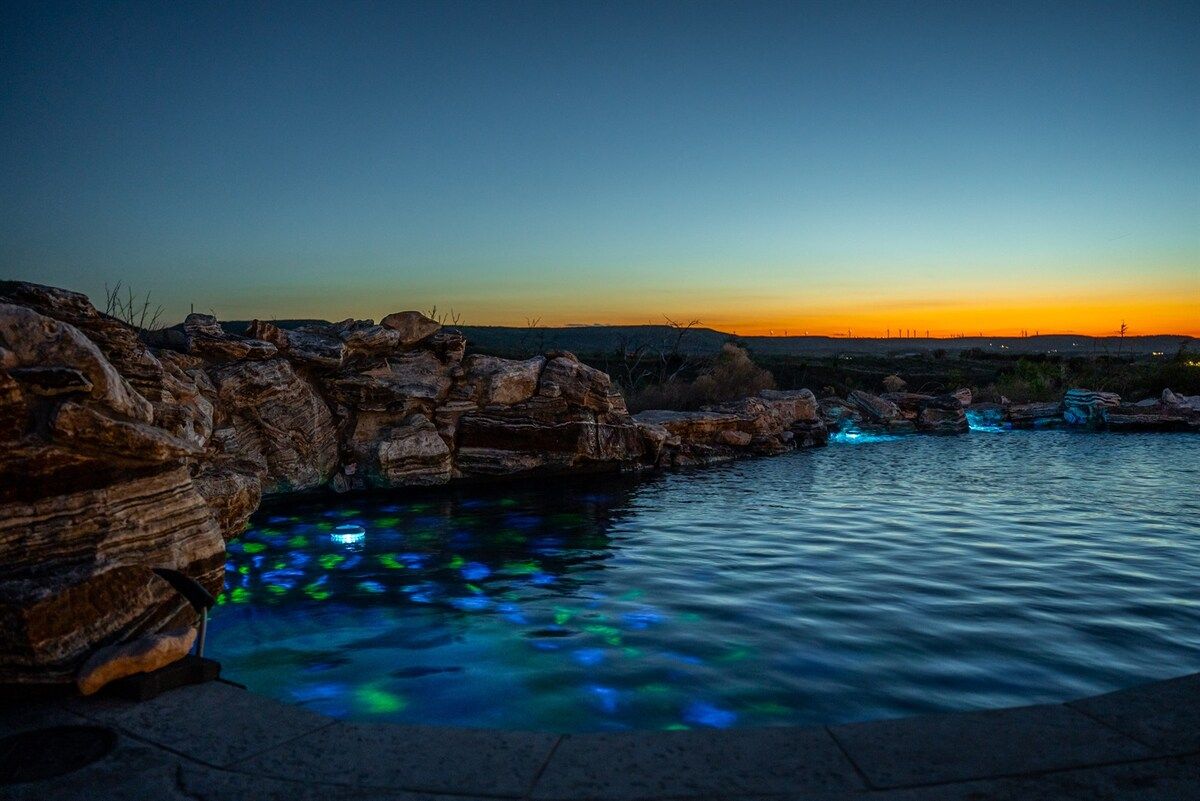 A pool with clear water reflecting light, surrounded by rock formations.