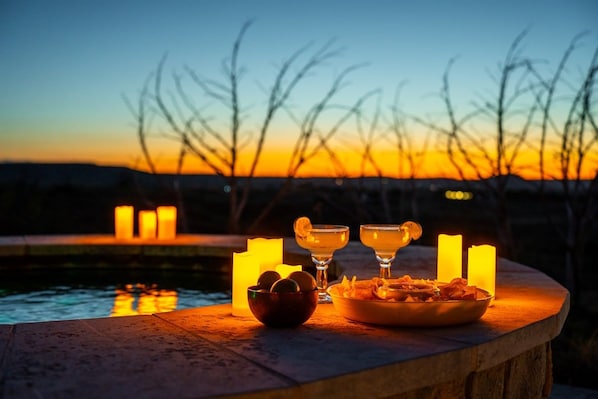 Una vista al atardecer con velas y aperitivos sobre un alero de piedra.