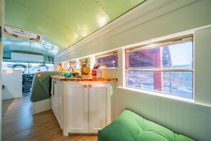 Een gezellig interieur met een keukenhoek, een eettafel en een raam met uitzicht op de omgeving.