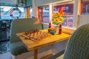 A cozy interior with a chessboard on a wooden table, a window with a view, and a vase with flowers.
